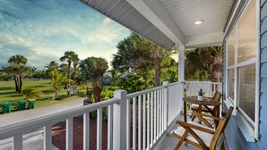 A covered porch with a white railing, wooden chairs, and a table. - 1- King bed/ 1- sofa bed/ 1.5bath Block from Beach (Cocoa Beach)
