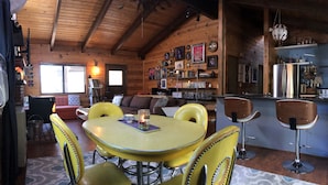 Un intérieur de chalet chaleureux comprenant un coin repas, un bar et un salon.