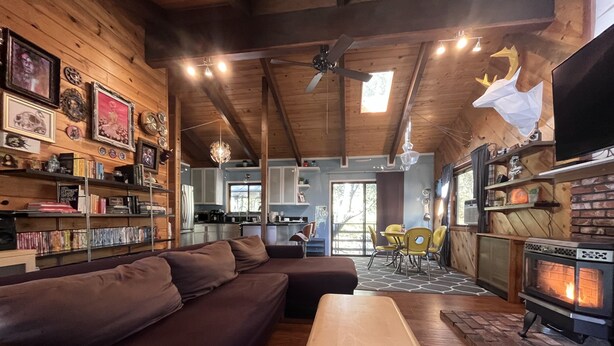 L’intérieur chaleureux d’un chalet avec un plafond en bois, une cheminée, un coin repas et une cuisine.