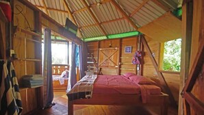 Een houten hutje met een bed, een kleine tafel en een raam.