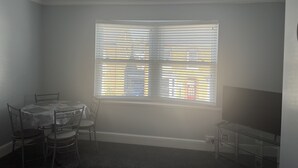 A room with a ceiling fan, a window with blinds, a dining table with chairs, and a small desk. - Spacious 1-bed Apartment in the Heart of Herne Bay (Herne Bay)