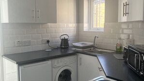 A compact kitchen with a washing machine, a microwave, and a toaster. - Spacious 1-bed Apartment in the Heart of Herne Bay (Herne Bay)