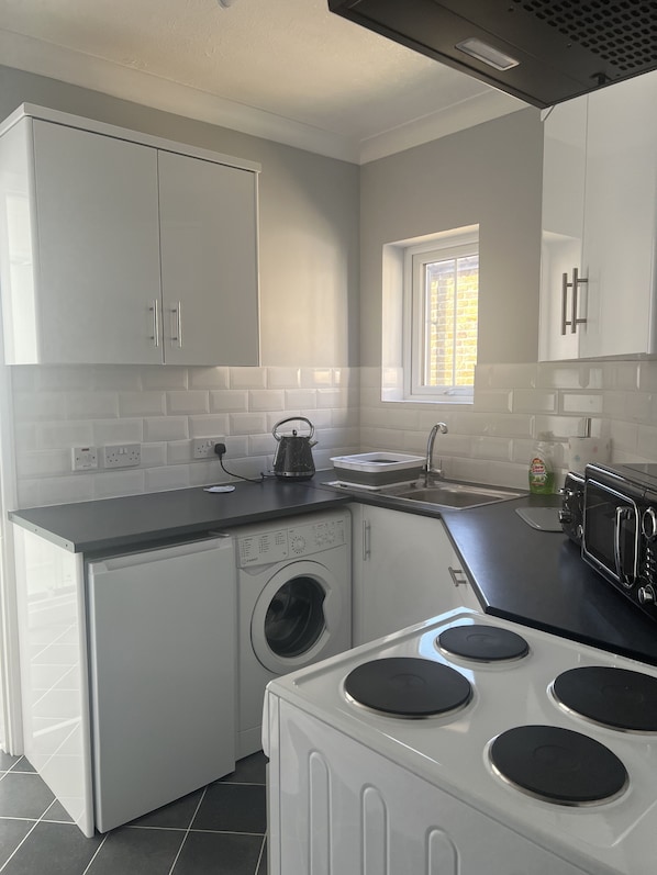 A compact kitchen with a washing machine, a microwave, and a toaster.