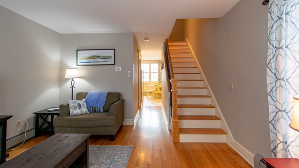 A living room with a wooden bench, a sofa, a lamp, and a staircase leading to another room. - Heart of Downtown Bar Harbor - fully airconditioned (Bar Harbor)