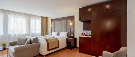 Una habitación de hotel moderna con una cama grande, un sofá, un escritorio y un armario.