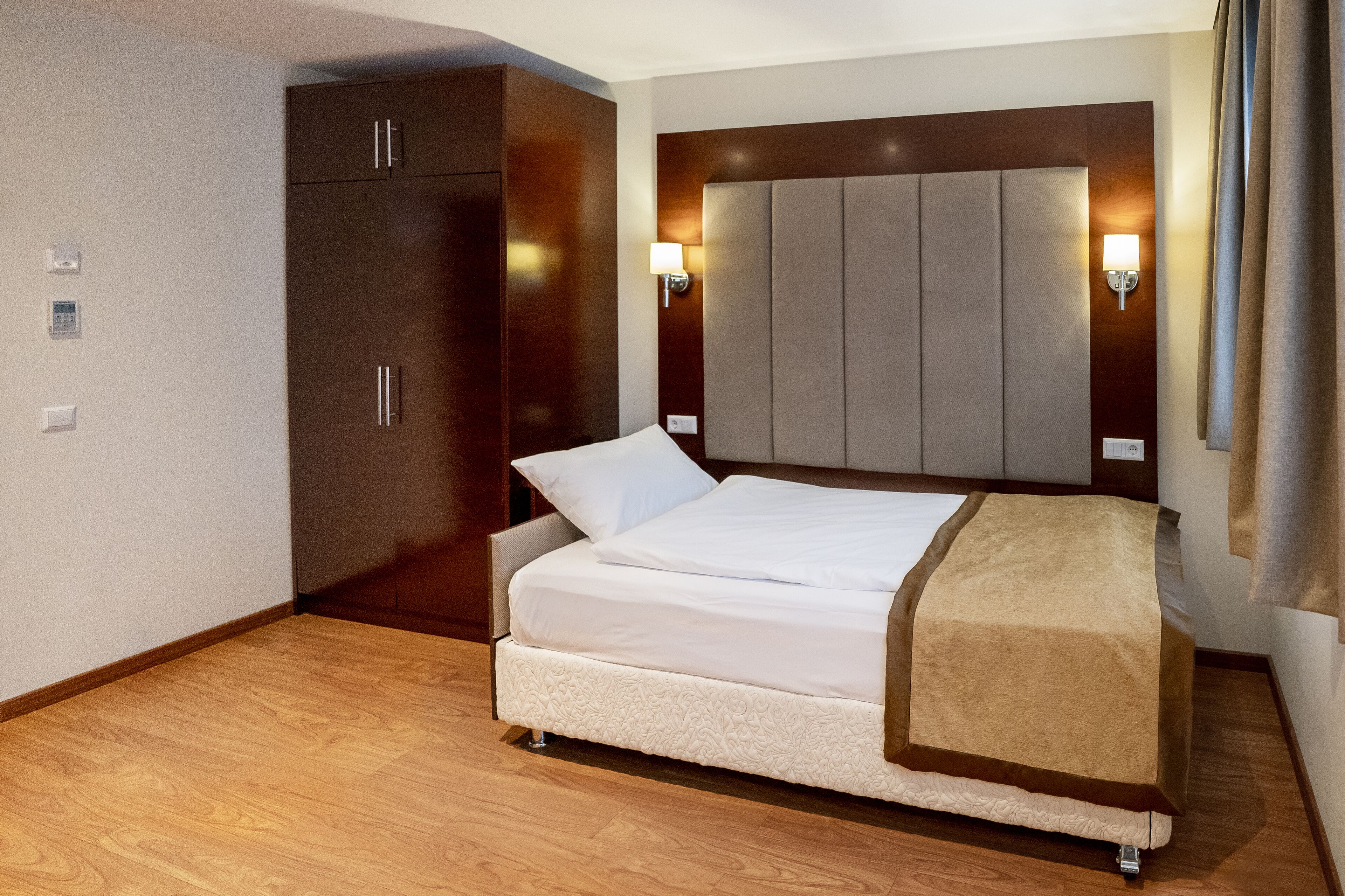 Ein Hotelzimmer mit einem Bett, einem Kleiderschrank und einem Kopfteil mit Wandleuchten.