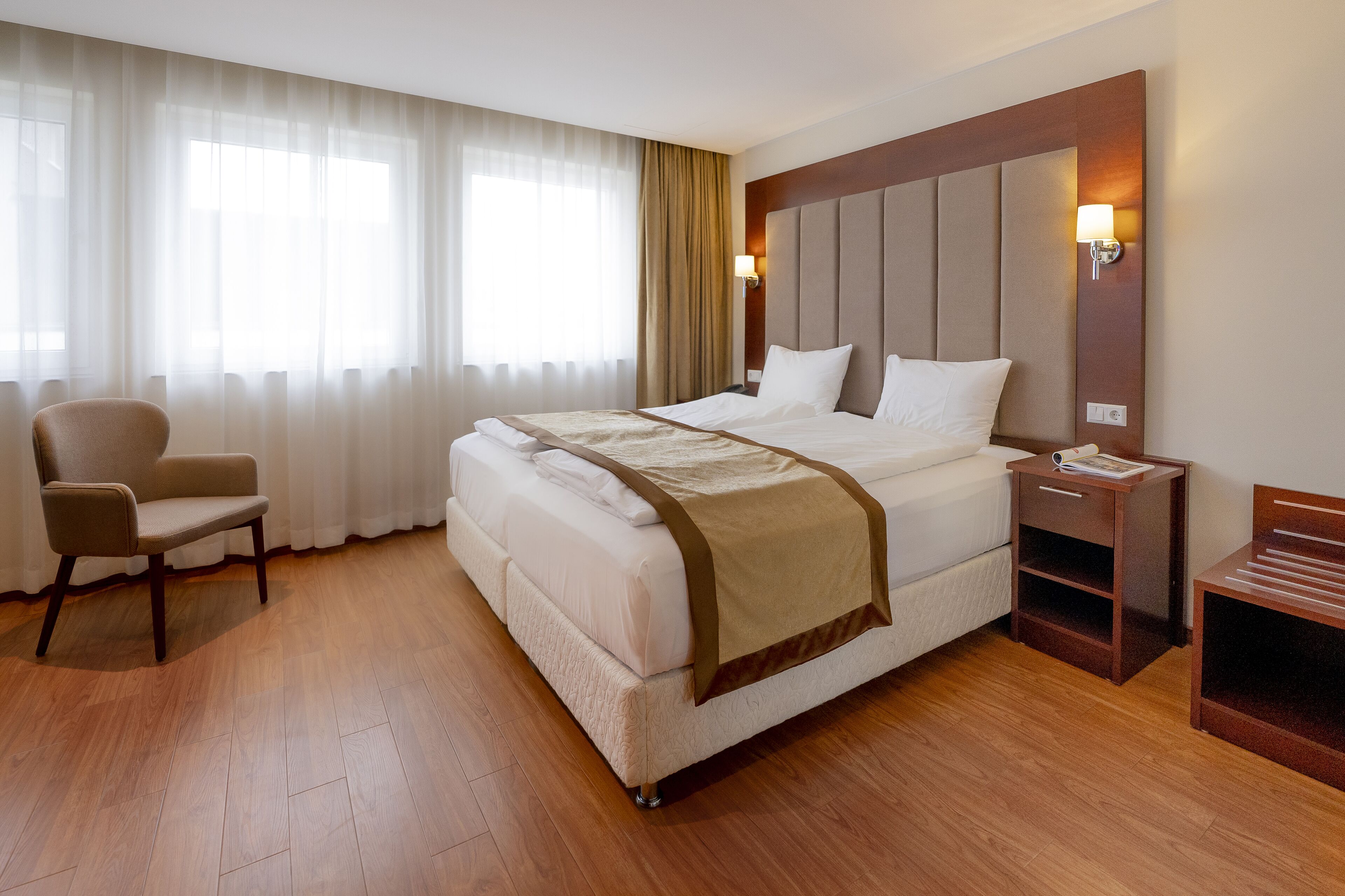 Ein Hotelzimmer mit einem großen Bett, einem Sessel, einem Nachttisch und einer Lampe.