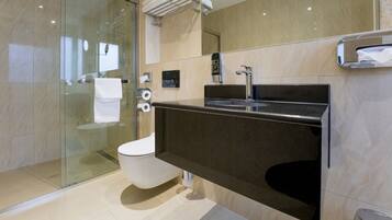 Une salle de bain moderne avec une douche à parois de verre, des toilettes blanches, un lavabo noir et un miroir au-dessus du lavabo.