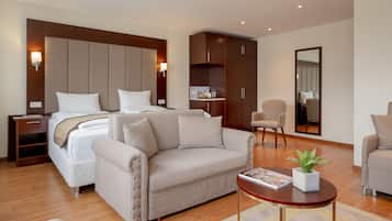 A hotel room with a bed, two sofas, a small table, a mirror, and a wardrobe.