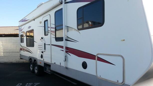 Un camping-car blanc, doté d’une porte latérale et d’une petite fenêtre, est garé sur un parking.