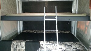 Un lit superposé avec une échelle, un matelas à motifs et un matelas uni.