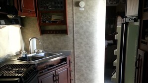 Une cuisine de taille réduite, équipée d’une cuisinière, d’un évier et de placards.