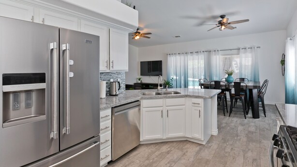 A modern kitchen with stainless steel appliances, white cabinetry, and a dining area with a table and chairs.