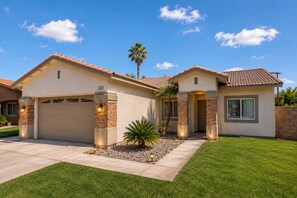 A two-story house with a garage, a small attached structure, and a well-maintained lawn.
