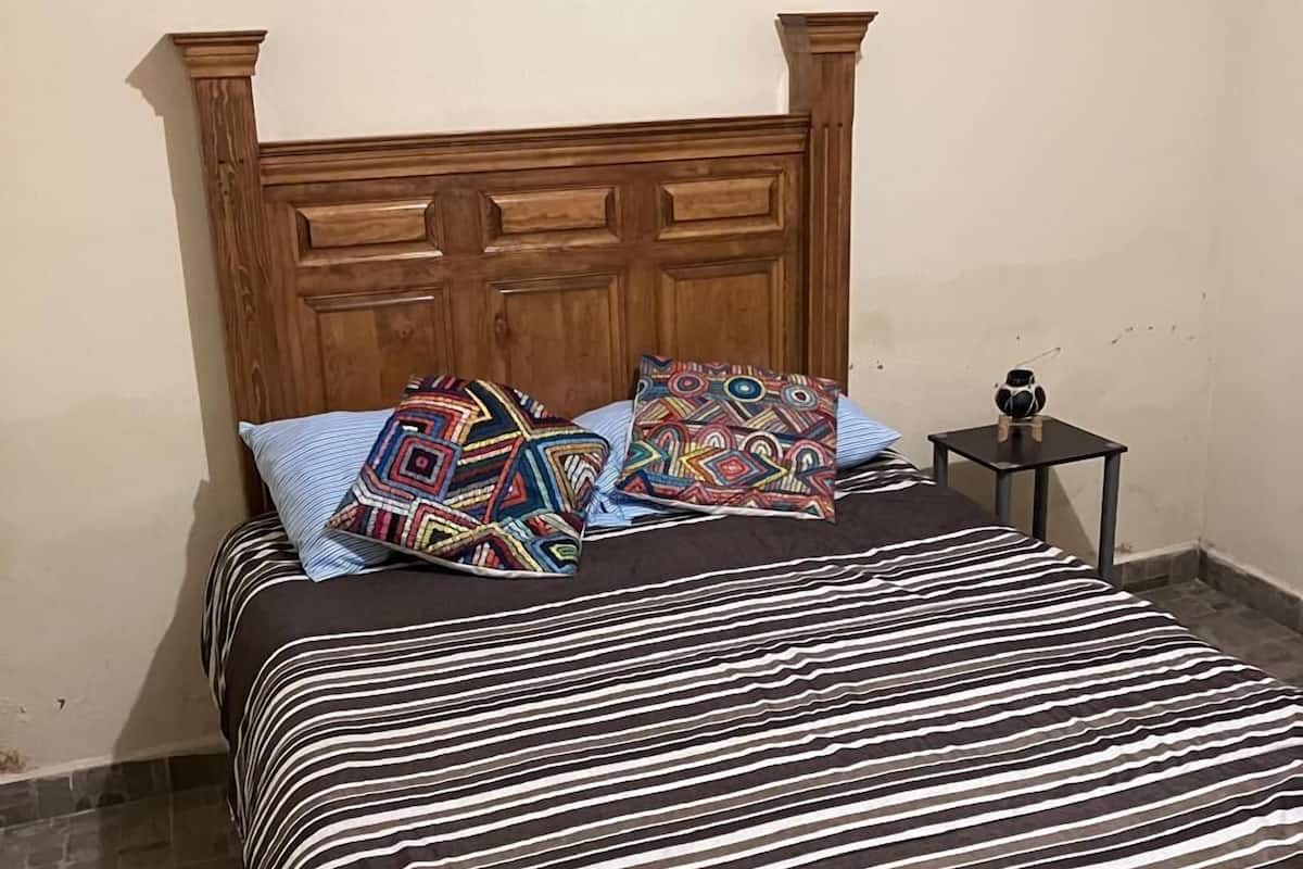 A bed with a striped bedspread, two patterned pillows, and a wooden headboard.
