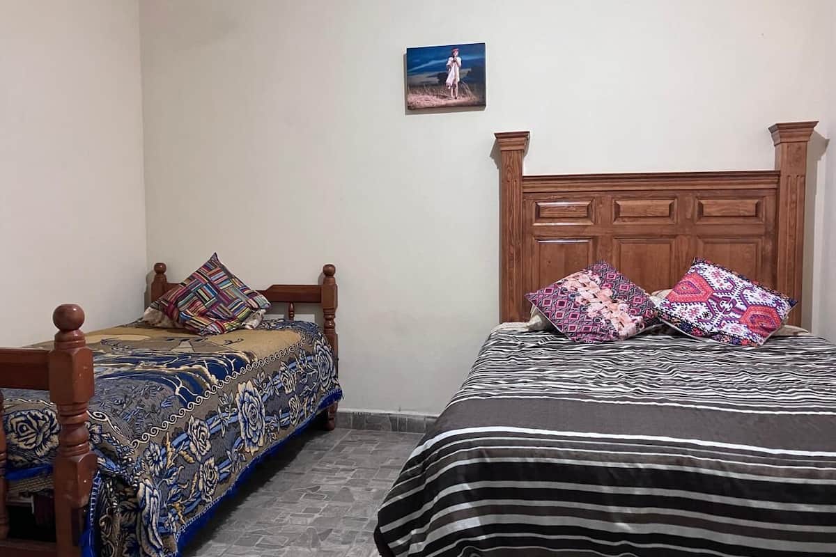 A bedroom with two beds, each with patterned bedding and wooden headboards.