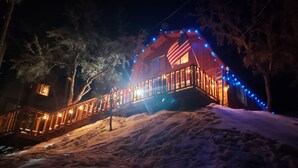A wooden cabin with a balcony, surrounded by snow and trees, illuminated by warm and blue lights. - BIG BEAR HIDEAWAY- 3 BED 2 BATH PRIVATE CUL-DE-SAC (Big Bear)