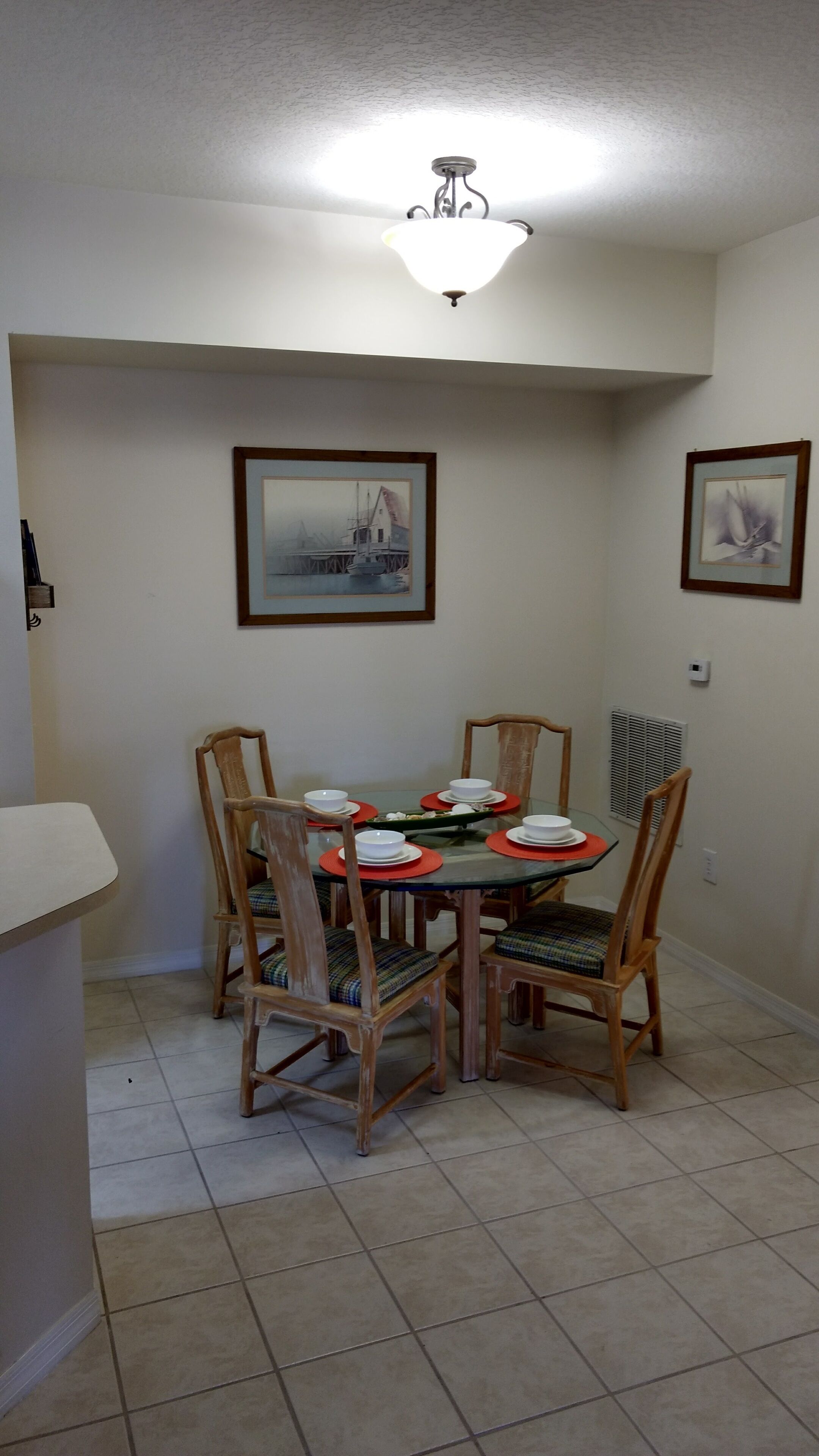 A dining area with a round table, six chairs, and a ceiling light fixture.