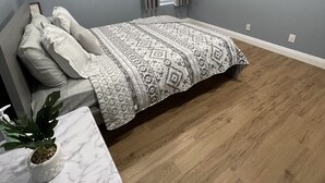 A bedroom with a bed, a bedside table with a plant, a window with curtains, and a wall-mounted mirror. - Vegas Resort 2-Bed Condo walking distance to Casinos (Ideal for Long Stays) (Las Vegas)