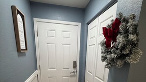 A hallway with a white door, a framed sign, and a wreath on the wall. - Vegas Resort 2-Bed Condo walking distance to Casinos (Ideal for Long Stays) (Las Vegas)