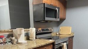 A kitchen with wooden cabinets, a stainless steel range, a microwave, and a granite countertop. - Vegas Resort 2-Bed Condo walking distance to Casinos (Ideal for Long Stays) (Las Vegas)