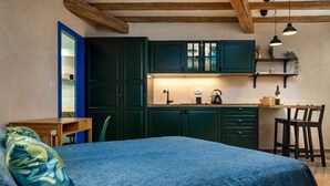 Ein gemütliches Zimmer mit Bett, Schreibtisch und einer Küchenzeile.