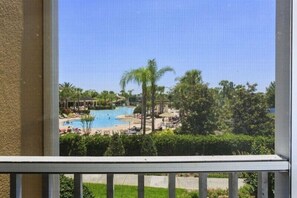 Vista de una zona de piscina con palmeras y sillas de descanso.