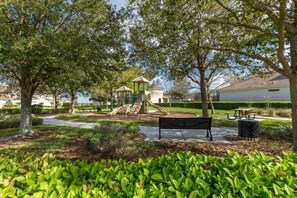 A park with a playground, benches, and trees. - Fantastic Condo - 2 Miles from Disney / Pool View / Windsor Hills (Kissimmee)