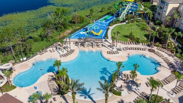 A resort with a large pool, a water park, and a view of the surrounding greenery.