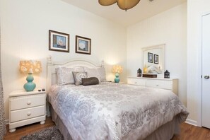 A bedroom with a large bed, two bedside tables, a dresser, and a mirror. - Beautiful Condo - Windsor Hills - 2 Miles Disney (Kissimmee)