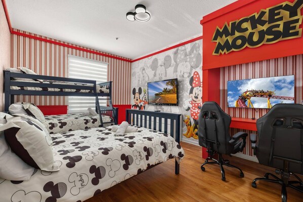 Habitación temática de Mickey Mouse con literas, un escritorio y dos sillas.