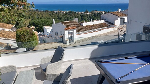 A pool table with two chairs, a view of the sea, and buildings in the background. - Nice villa in La Cala de Mijas  Spain with heated pool and  sea ​​view. (Las Lagunas de Mijas)