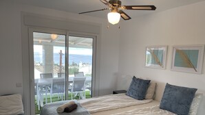 A bedroom with a bed, two pillows, a ceiling fan, and a view of the outdoors. - Nice villa in La Cala de Mijas  Spain with heated pool and  sea ​​view. (Las Lagunas de Mijas)
