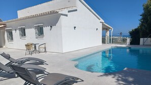 A white building with a swimming pool, outdoor seating, and a view of the sea. - Nice villa in La Cala de Mijas  Spain with heated pool and  sea ​​view. (Las Lagunas de Mijas)