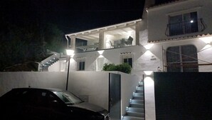 A two-story house with a covered porch, a staircase, and a car parked in the driveway. - Nice villa in La Cala de Mijas  Spain with heated pool and  sea ​​view. (Las Lagunas de Mijas)
