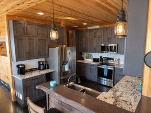 A modern kitchen with granite countertops, stainless steel appliances, and wooden cabinetry.