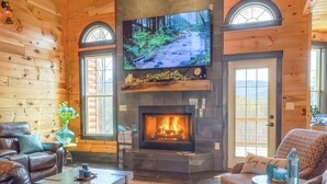 A log cabin interior with a fireplace, television, and seating area.