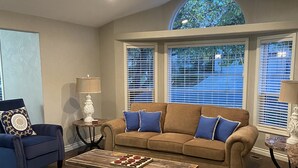 A living room with a brown sofa, blue cushions, a coffee table, and a patterned rug. - Brookdale Meadows sleeps 6 (Medford)