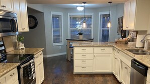 A modern kitchen with white cabinets, stainless steel appliances, and a wooden floor. - Brookdale Meadows sleeps 6 (Medford)