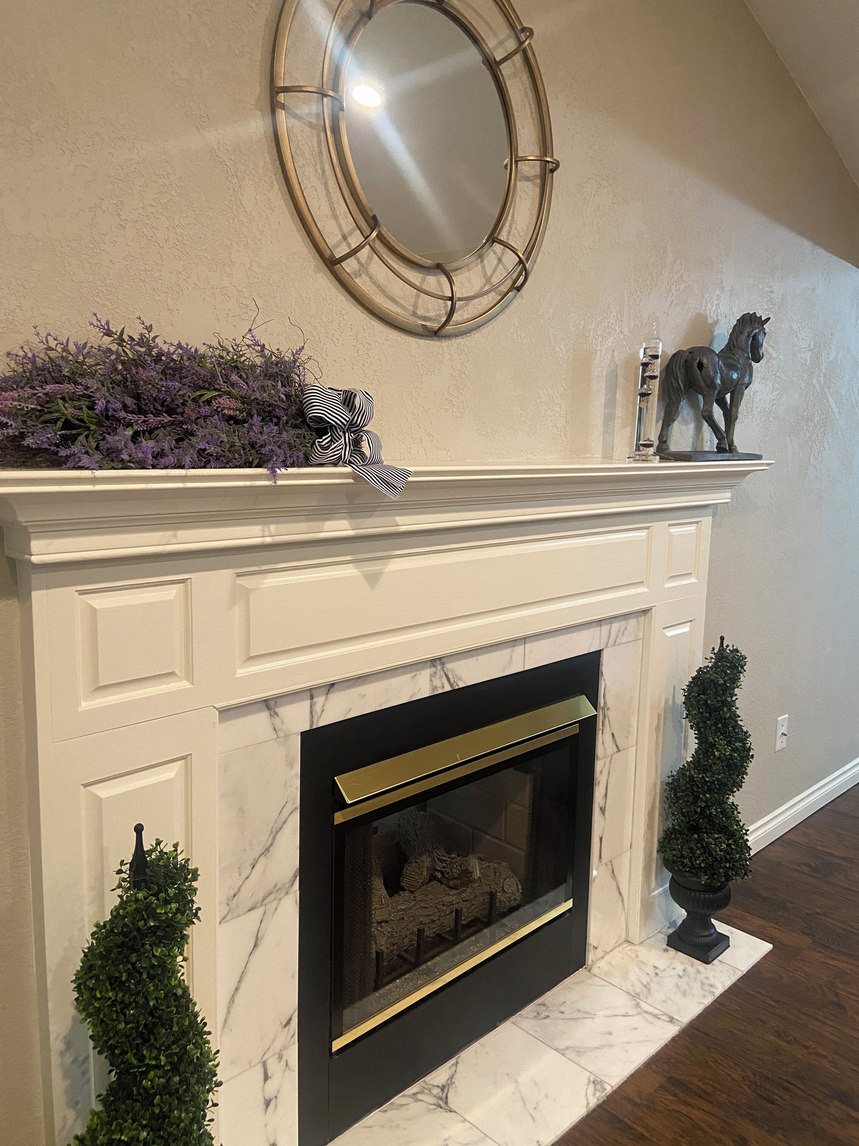A fireplace with a marble surround, a decorative mirror above it, and a small horse statue on the mantel.