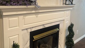 A fireplace with a marble surround, a decorative mirror above it, and a small horse statue on the mantel. - Brookdale Meadows sleeps 6 (Medford)