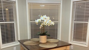 A dining area with a wooden table and benches, a vase with white flowers, and a ceiling fan. - Brookdale Meadows sleeps 6 (Medford)