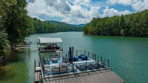 A dock with a covered seating area, a small boat, and a cabin. - Country Roads - Lake Front | Hot Tub | Pool Table | Shuffle Board | Arcades (Morganton)