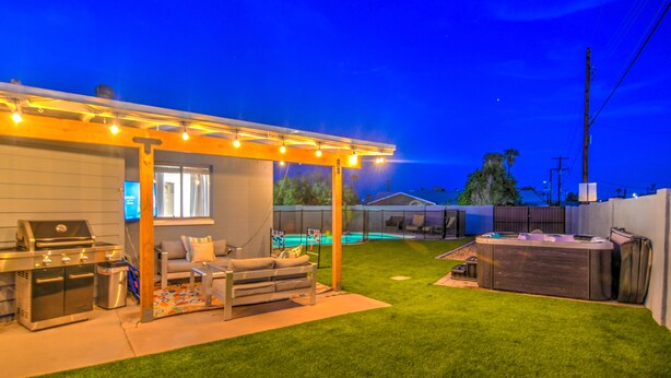 A backyard with a barbecue area, a hot tub, and a covered seating area with string lights. - South Scottsdale Poolside Getaway! (Scottsdale)