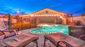 A swimming pool with lounge chairs and a covered area with string lights. - South Scottsdale Poolside Getaway! (Scottsdale)