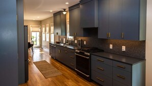 Una cocina moderna con armarios oscuros, una estufa negra y un salpicadero de azulejos.
