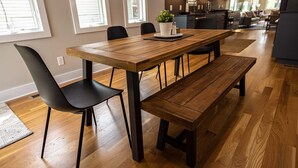 Un comedor moderno con una mesa de madera, sillas negras y un banco.