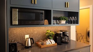 Una cocina moderna con armarios oscuros, un microondas y una cafetera en la encimera.