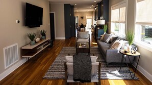 Un salón amplio con sofá, mesa de centro y televisor. Hay plantas en macetas y una chimenea.
