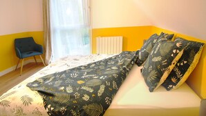 Un dormitorio con cama, una silla y una ventana con cortinas.